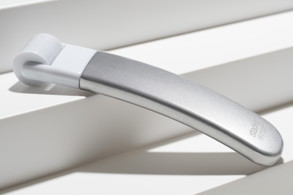 Sleek, Sustainable, Durable Aluminum Microneedling Tool with Replaceable Roller Head sitting on a shelf.