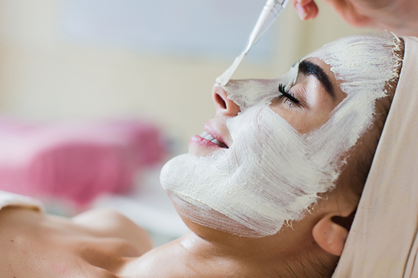Woman at a spa relaxing while receiving a chemical peel. She is being informed by the aesthetician on chemical peels 101: Everything you need to know.