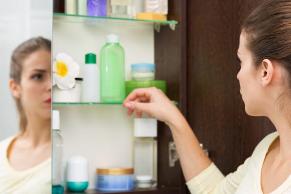 Woman looking in her bathroom cabinet to analyze if the skincare has gone bad